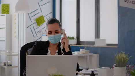 entrepreneur with protective face mask discussing on landline