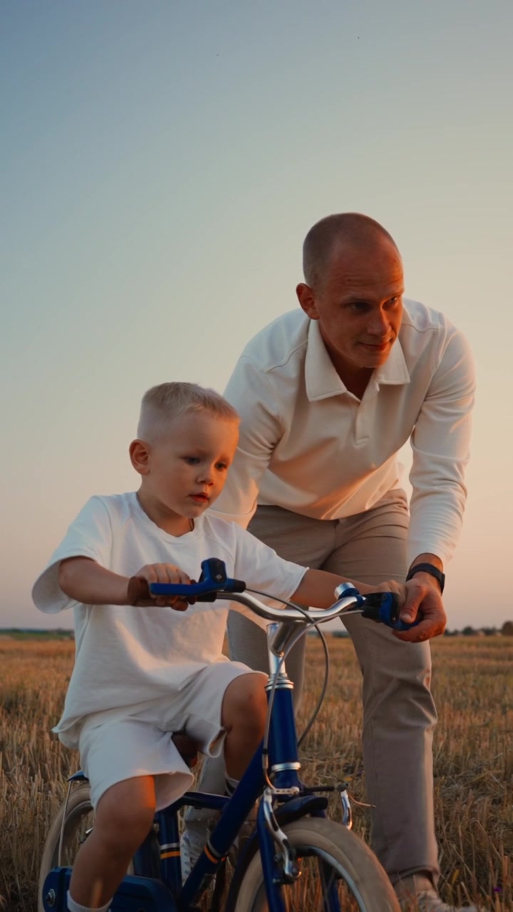 Father Teaching Young Son to Ride a Bicycle in a Field