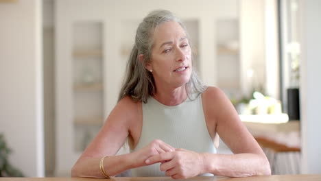 Mujer-Caucásica-Con-Pelo-Gris-Sentada-A-La-Mesa,-Mirando-Hacia-Arriba