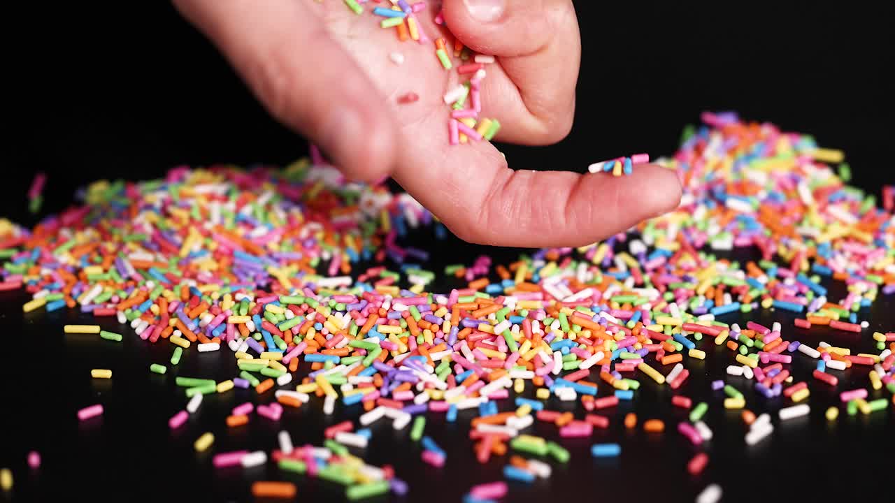 Mani con zuccherini colorati su una superficie