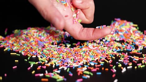 hands interacting with colorful sprinkles on surface