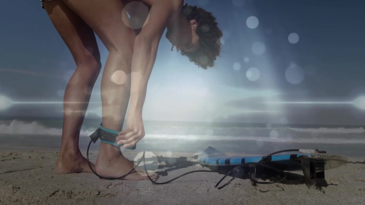 Surfer Attaching Leash to Ankle on Sandy Beach