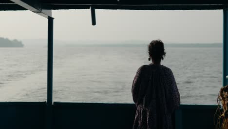 fotografía en cámara lenta de una mujer turista admirando el mar desde un barco tradicional en la india