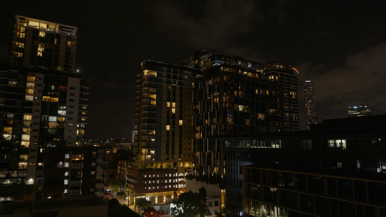 Panoramica a sinistra, lo skyline di Brisbane di notte con grattacieli residenziali e negozi illuminati