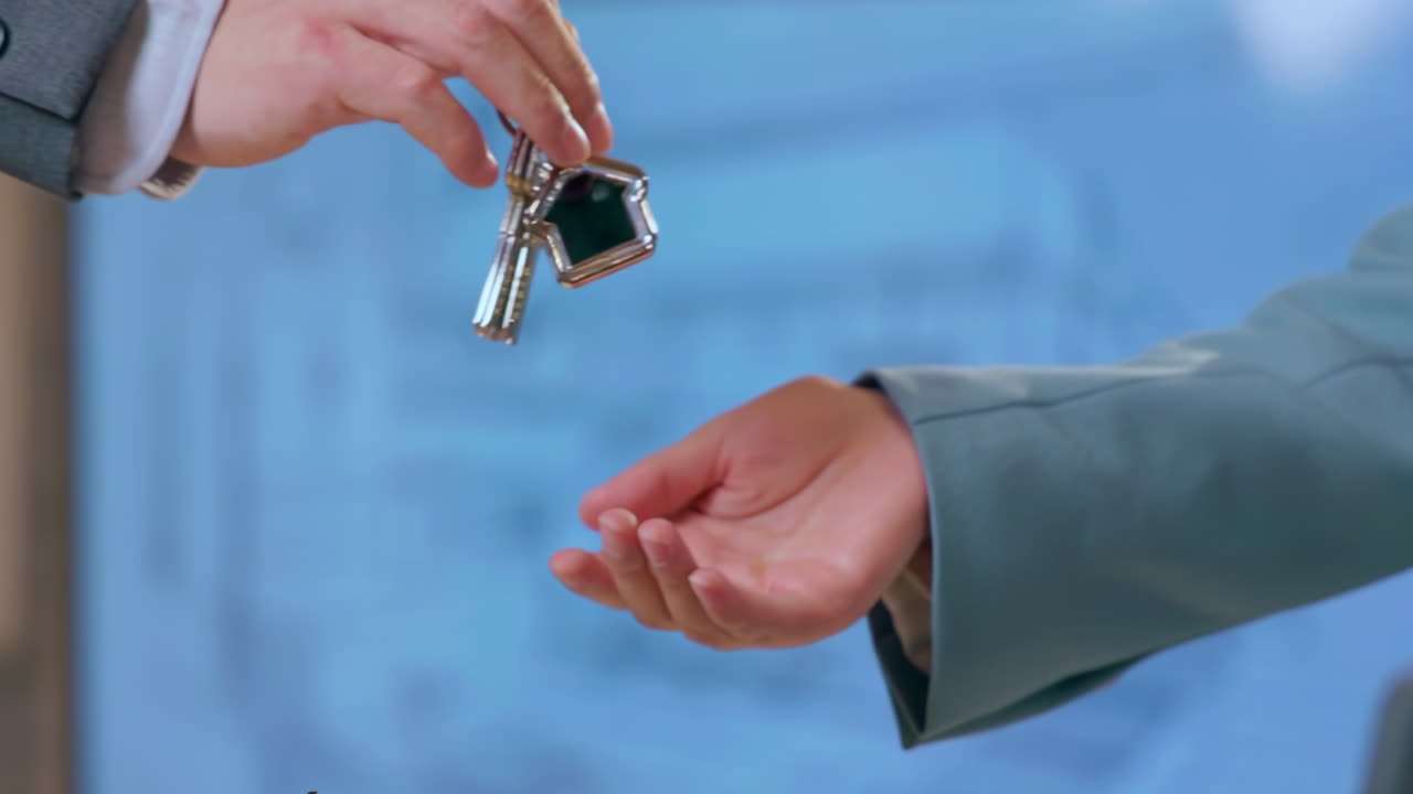 Broker Business man in the office gives the keys to the house to a woman, hands close-up. Concept of buying real estate, mortgage. Investment in a new building, smart home rental