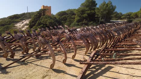 pan right of rusty anchors lined up in rows used for tuna fishing nets