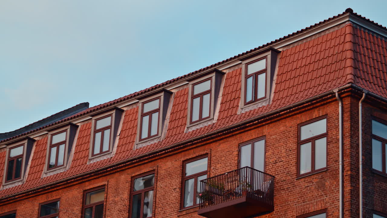 Facciata di un vecchio edificio residenziale in mattoni con finestre, balconi e tetto di tegole in un ambiente urbano. Copenaghen, Danimarca