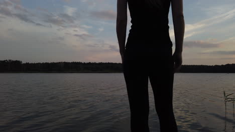 woman on a small pier admires the wonderful lake at sunset