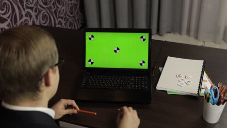 hombre haciendo una llamada de video en línea en una computadora portátil. pantalla verde. educación a distancia