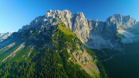 Impresionante-Vista-Aérea-A-Través-De-Laderas-Cubiertas-De-Bosques-De-Picos-De-Las-Montañas-Wilder-Kaiser-Iluminadas-Por-El-Sol