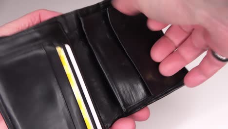 manos humanas en busca de monedas de euro en una billetera de cuero negra
