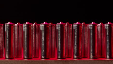 Silver batteries AA and AAA in neon light close-up. Double-A battery is a standard size single cell cylindrical dry battery. Batteries are common in portable electronic devices. An AA battery is composed of a single electrochemical cell that may be either a primary battery or a rechargeable battery.