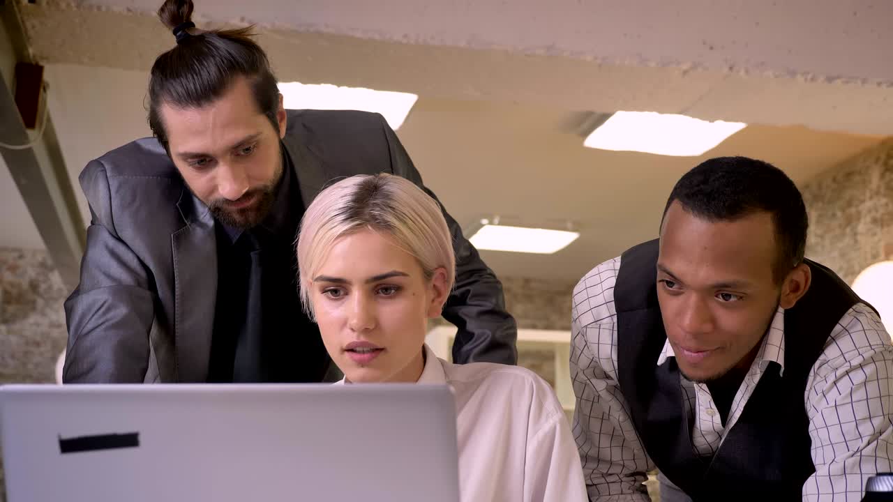 Three multy-ethnic workers discuss idea on laptop, coworking concept, communication concept, business concept