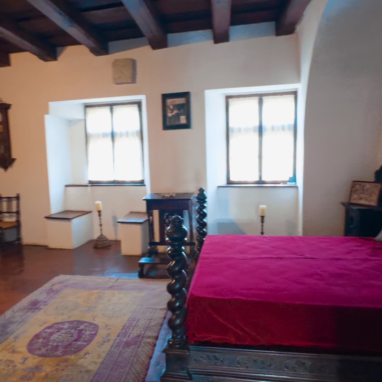 Interno del castello medievale di Bran a Brasov, Romania. Inquadratura di un grande letto in legno con copertura rossa
