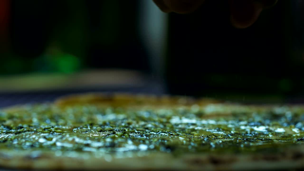 el chef agrega condimentos a la masa de la pizza