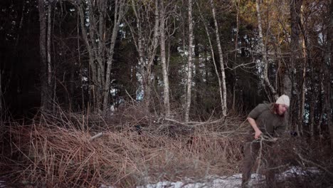 un hombre recoge leña en un día de invierno, y lo apila a un lado - toma estática