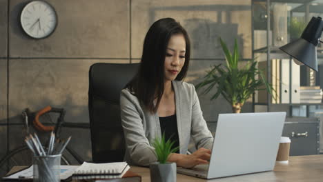 Joven-Y-Atractiva-Trabajadora-De-Oficina-Sentada-En-La-Computadora-Portátil-En-El-Escritorio,-Trabajando-Y-Pensando