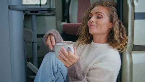 serene woman enjoy morning beverage sitting campervan stairs in sweater close up