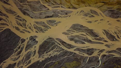 vista aérea superior de un río glaciar que fluye en un valle, con muchas ramas, sobre arena oscura, en islandia
