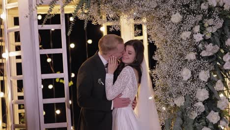 romantic wedding kiss under floral arch