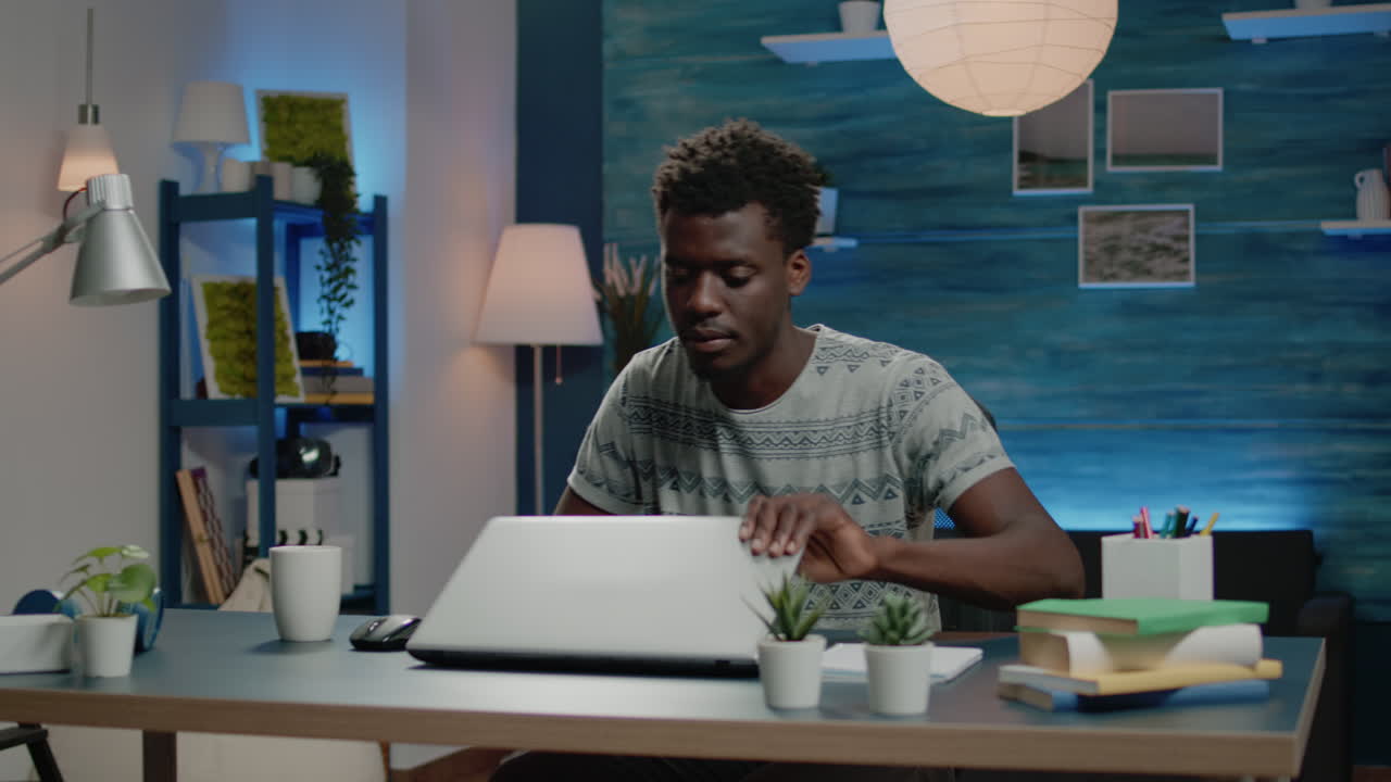 Black man working from home with laptop and coffee at desk