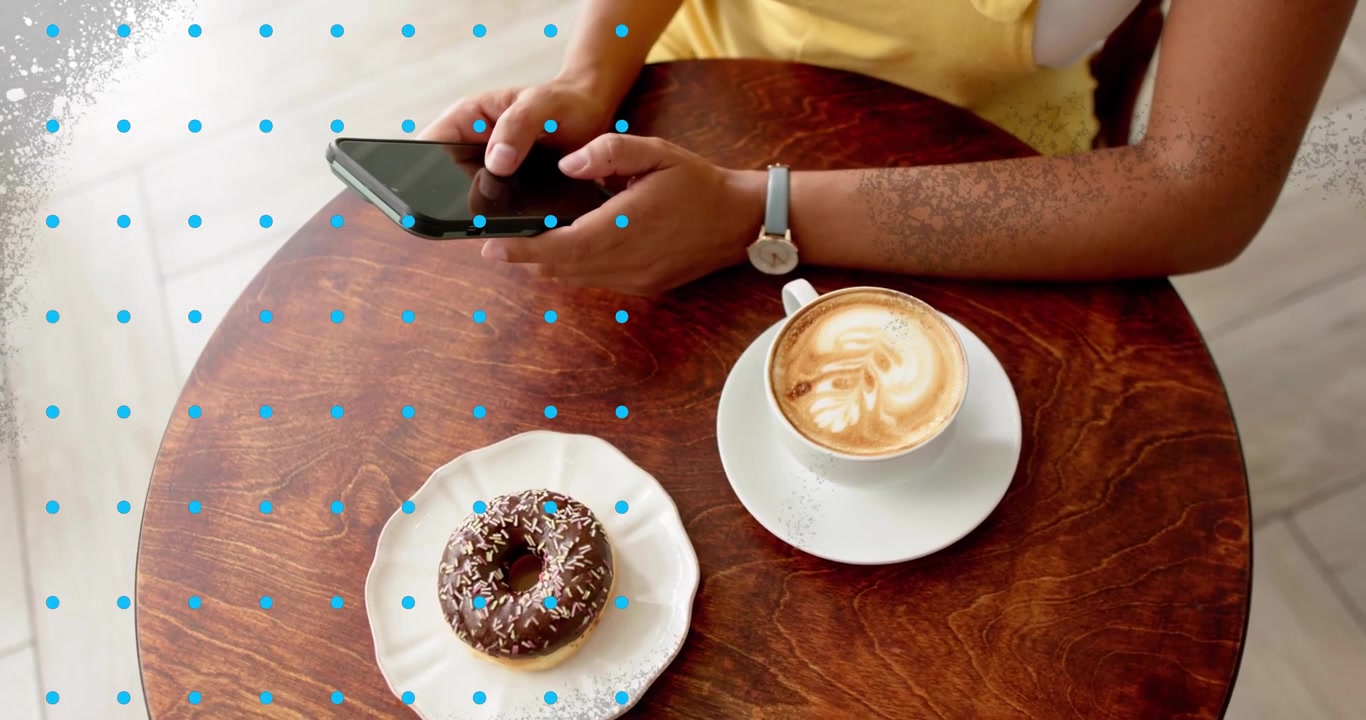 Donna che tiene uno smartphone sopra un tavolo da caffè toccando per la scansione AR, con una griglia blu che si sovrappone a un latte e una ciambella.