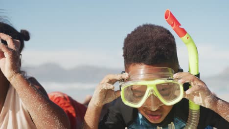 African-american-brother-and-sister-wearing-scuba-diving-mask-with-a-snorkel-at-the-beach