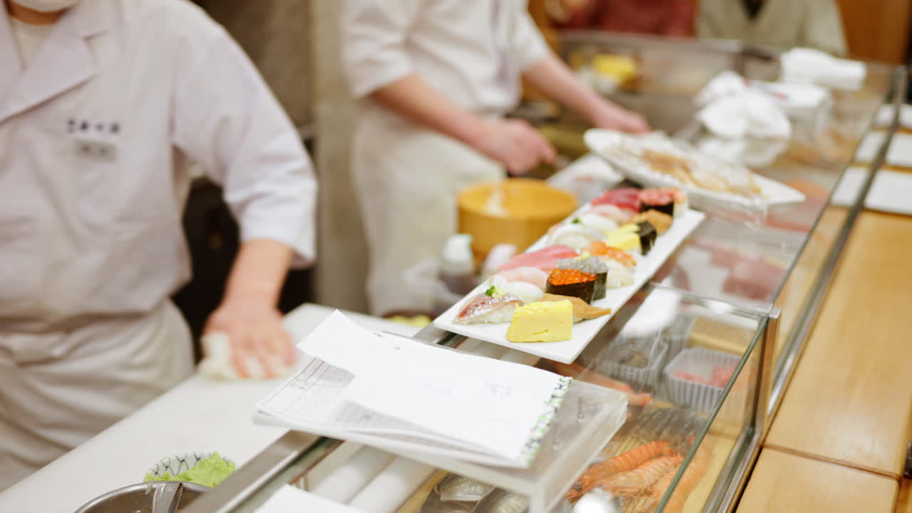 Close up of a chef preparing nigiri on a white plate at the Tsukiji Fish Market in Japan