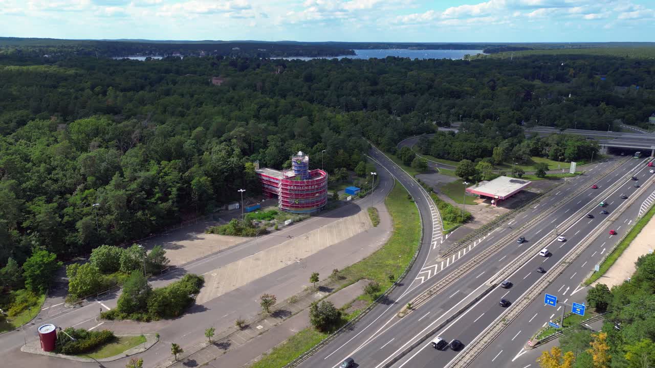 Cars driving on a freeway interchange surrounded by forest leading to a lake on a cloudy day. Beautiful aerial view flight speed ramp hyper motion time lapse
