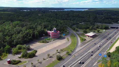 cars driving on a freeway interchange surrounded by forest leading to a lake on a cloudy day. beautiful aerial view flight speed ramp hyper motion time lapse