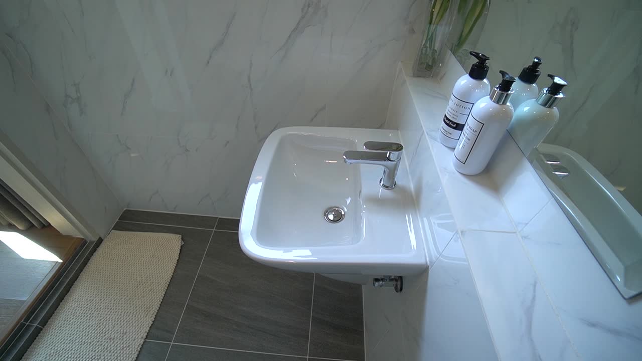 lavabo de cerámica blanca limpia y diseño interior de baño con baldosas grises, sin gente