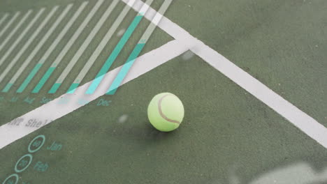 neon green tennis ball lying on court showing white lines, court texture with diagonal overlay