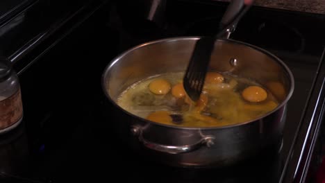 young adult male scrambling a large stainless steel pan full of organic eggs