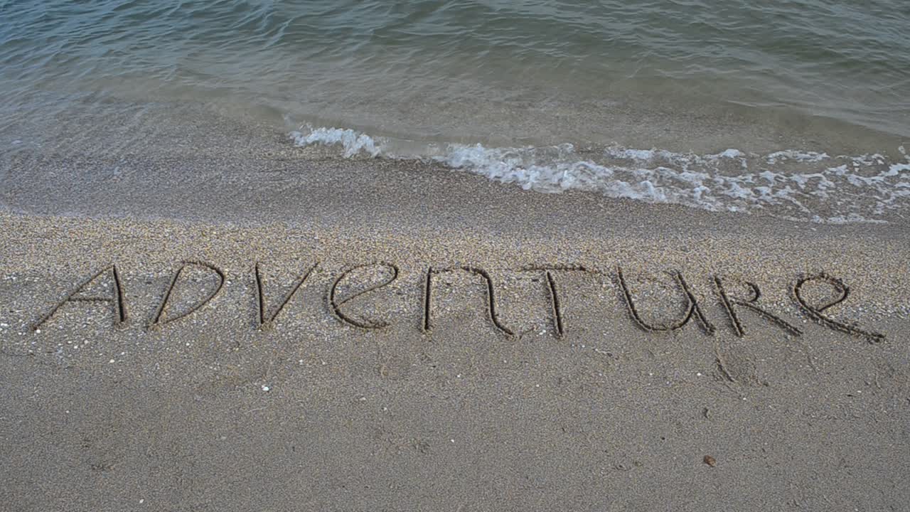 Adventure inscription on sand, on the beach. Shooting on the beach