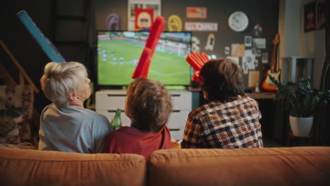 friends watching soccer game on tv and celebrating goal at home
