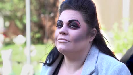 Young-lady-with-dark-make-up-and-black-hair-smiles-at-the-camera,-slow-mo