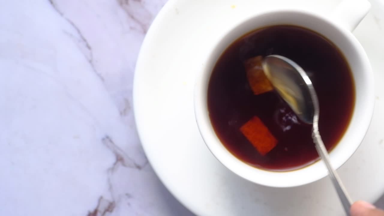 Close-up of a cup of coffee or tea with sugar cubes and a spoon