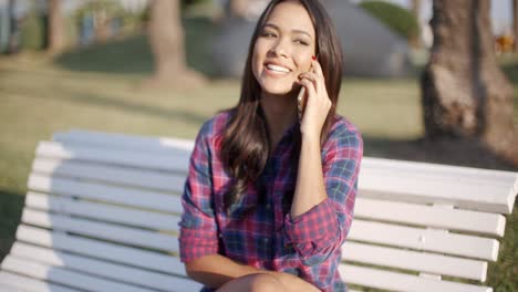 Mujer-Con-Teléfono-Celular-En-El-Banco-Del-Parque