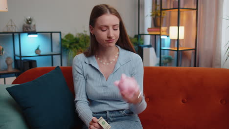 mujer joven pobre con una alcancía y un billete de un dólar, crisis financiera, bancarrota, pobreza