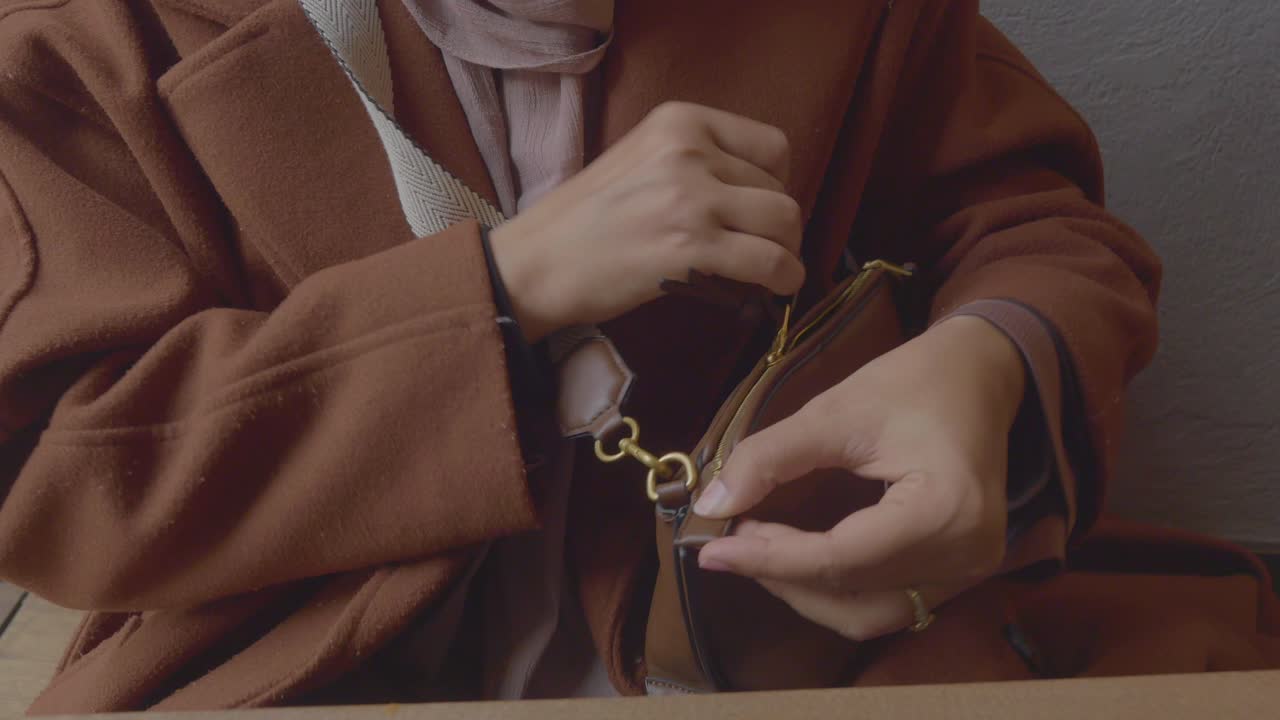 여자가 갈색 드백을 열고