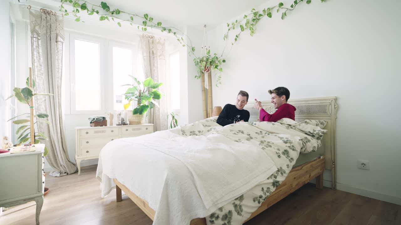 Due giovani uomini che parlano e si danno il cinque in una camera da letto luminosa.