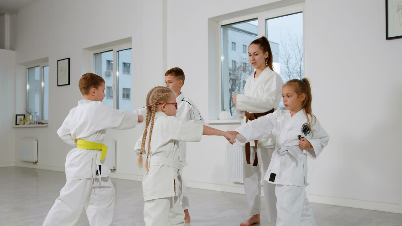 niños en kimono blanco y maestro en clase de artes marciales