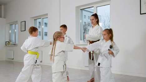 kids in white kimono and teacher in martial arts class