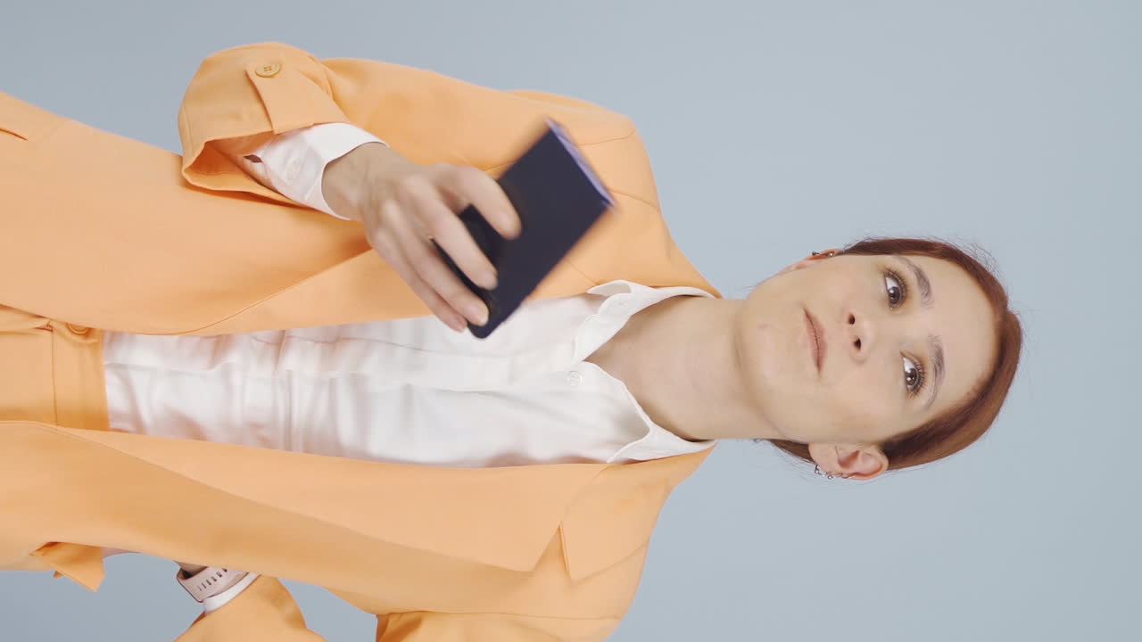 스트레스를 받은 사업가 여성의 수직 비디오, 손에 전화와 불확실한 표정.