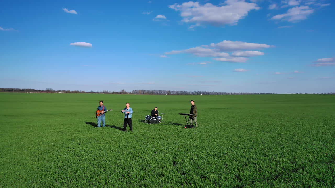 Musical performance in the green field on sunny spring day. Circle movement footage around group of musicians. Nature background.