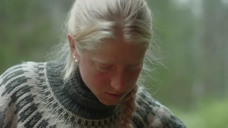 close-up ofthe face of a beautiful nordic blond girl picking stinging nettles with bare hands, urtica, in the finish forest, on the karhunkierros trail in the oulanka national park, finland