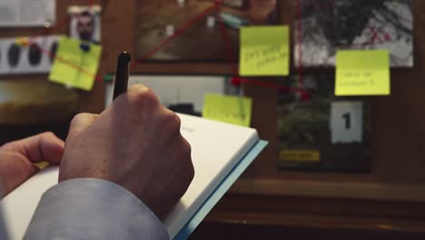delante de la tabla de pruebas, el detective captura detalles importantes tomando notas en un cuaderno