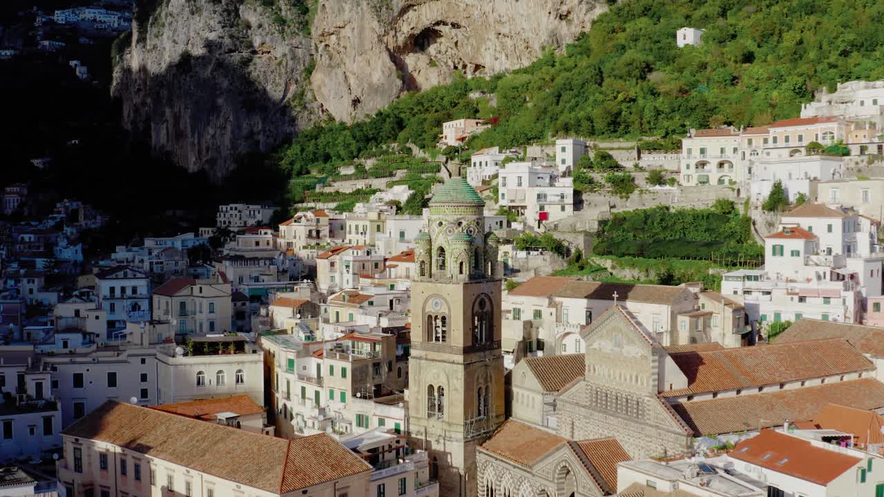 Volo di drone aereo che orbita intorno al campanile del Duomo di Sant'Andrea ad Amalfi. Architettura italiana storica che risplende al caldo sole serale estivo sulla Costiera Amalfitana.