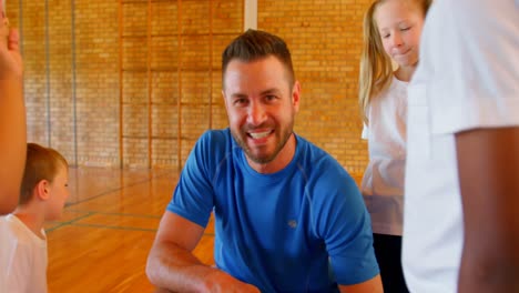 Sports-teacher-and-schoolkids-discussing-over-clipboard-in-the-basketball-court-4k