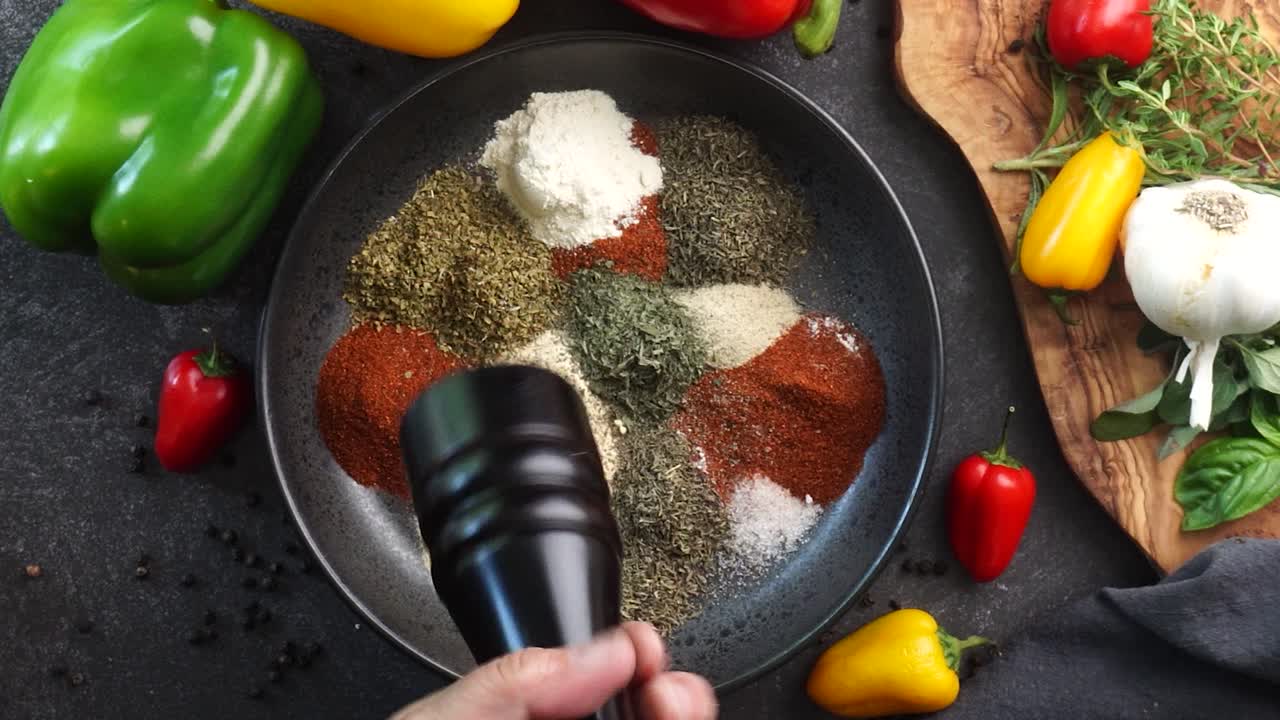 Making a vibrant Cajun Spice Blend, mixing red paprika, cayenne pepper, oregano, thyme, white garlic onion powder and black pepper in a bowl, creating a striking contrast against a black background.